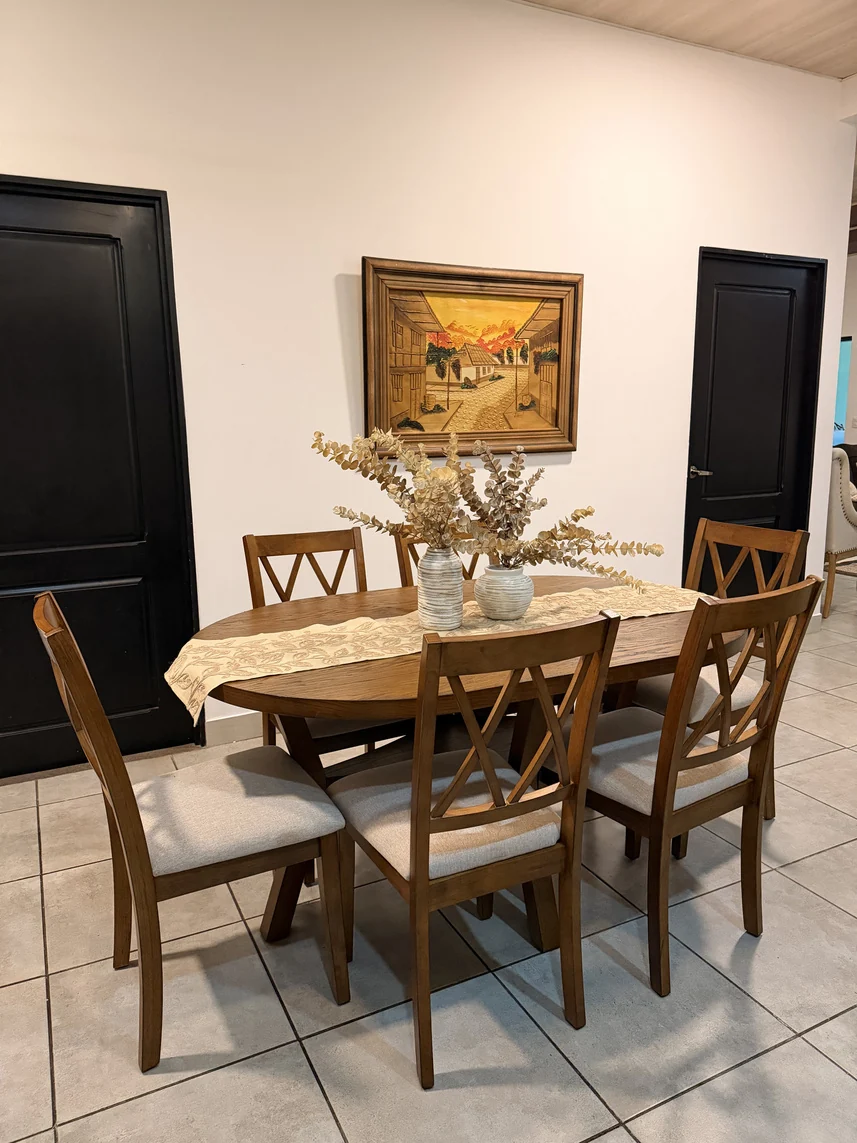 Comedor con mesa y sillas de madera, centro de mesa floral y arte en la pared