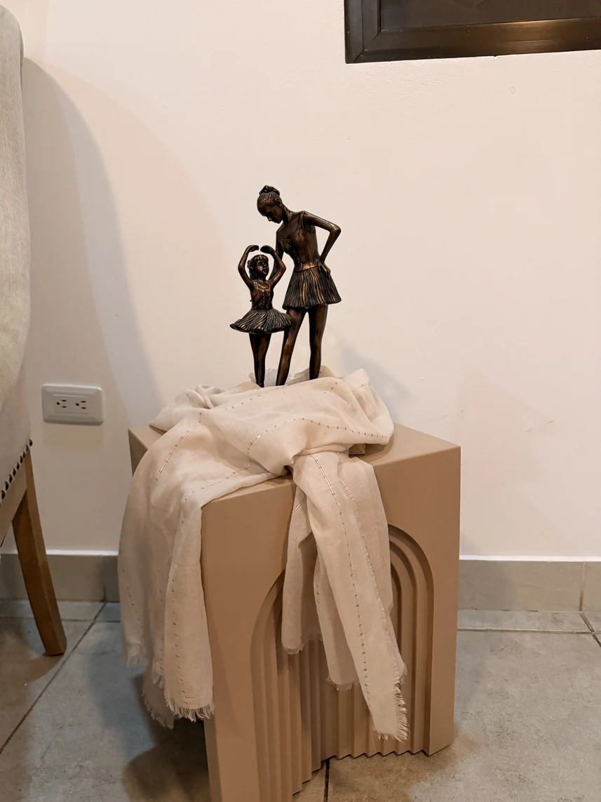 Escultura sobre una mesa auxiliar con textiles en tonos beige